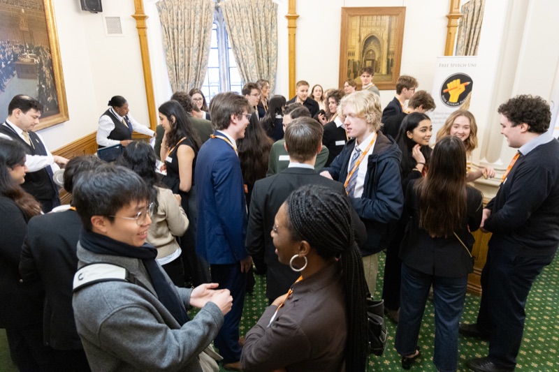 Students talking in groups in a wood-panelled Commons room hung with oil paintings