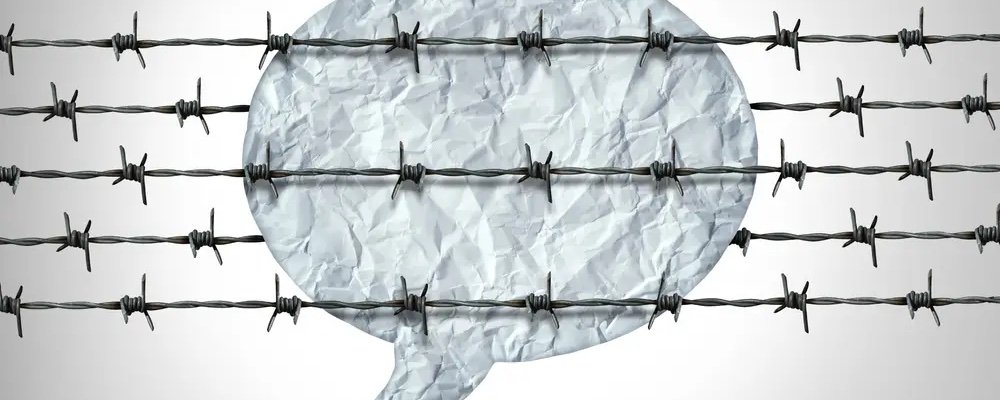 Speech bubble trapped behind barbed wire, representing censorship of free speech at universities